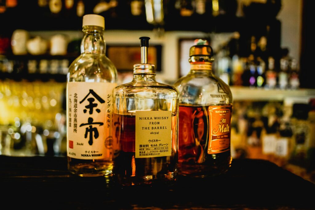 pexels-photo-372959-372959 Selection of Japanese whisky bottles displayed in a dimly lit bar setting.